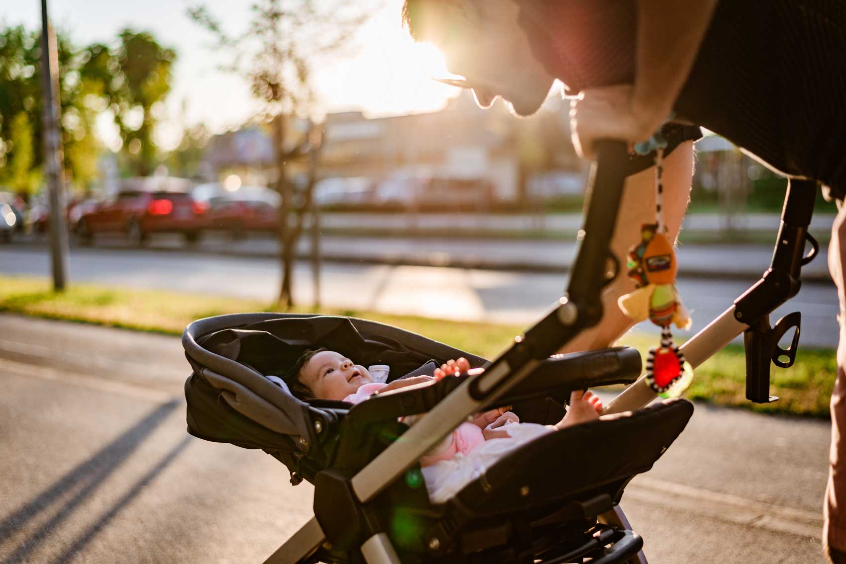 Family walk around the neighborhood. Single father is taking care of newborn baby while walking on sunset. Baby is in stroller.